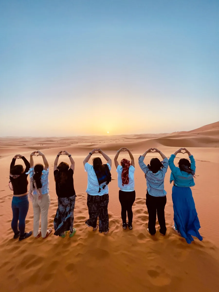 Travelers on the Erg Chebbi dunes near Merzouga at sunset